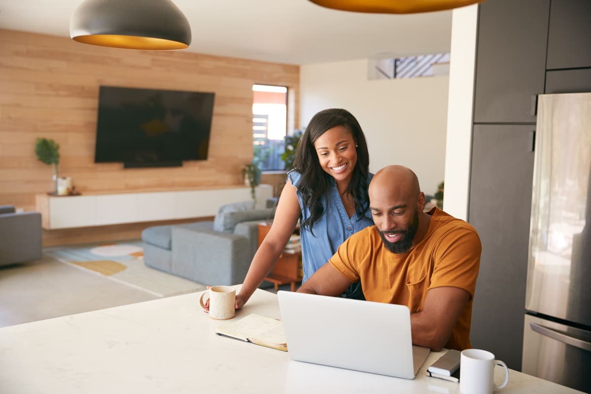 A couple reviewing home finances together on a laptop at home.