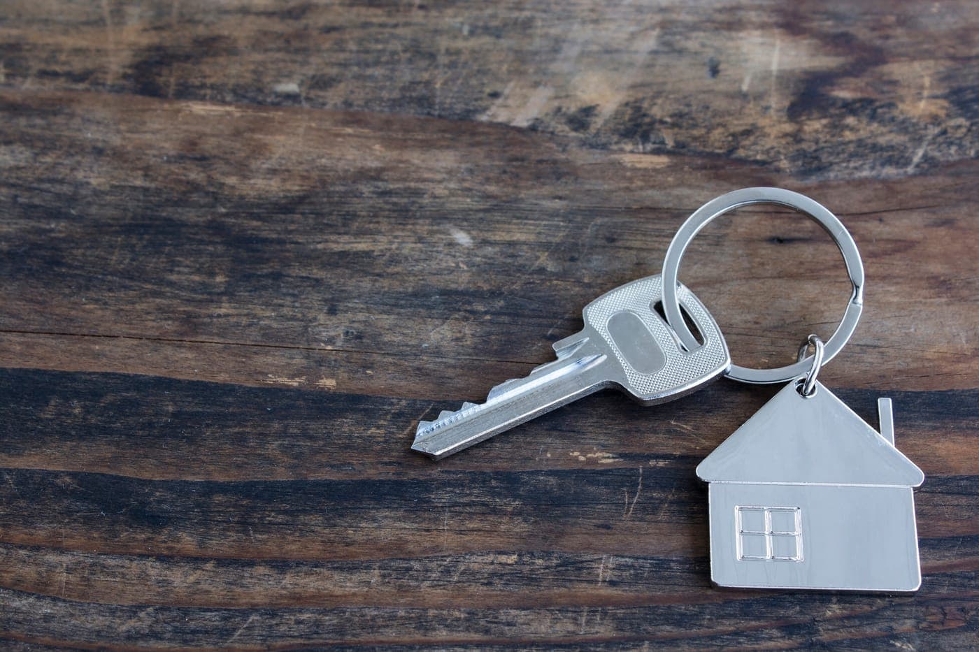 A set of house keys resting on a table in front of a new home.